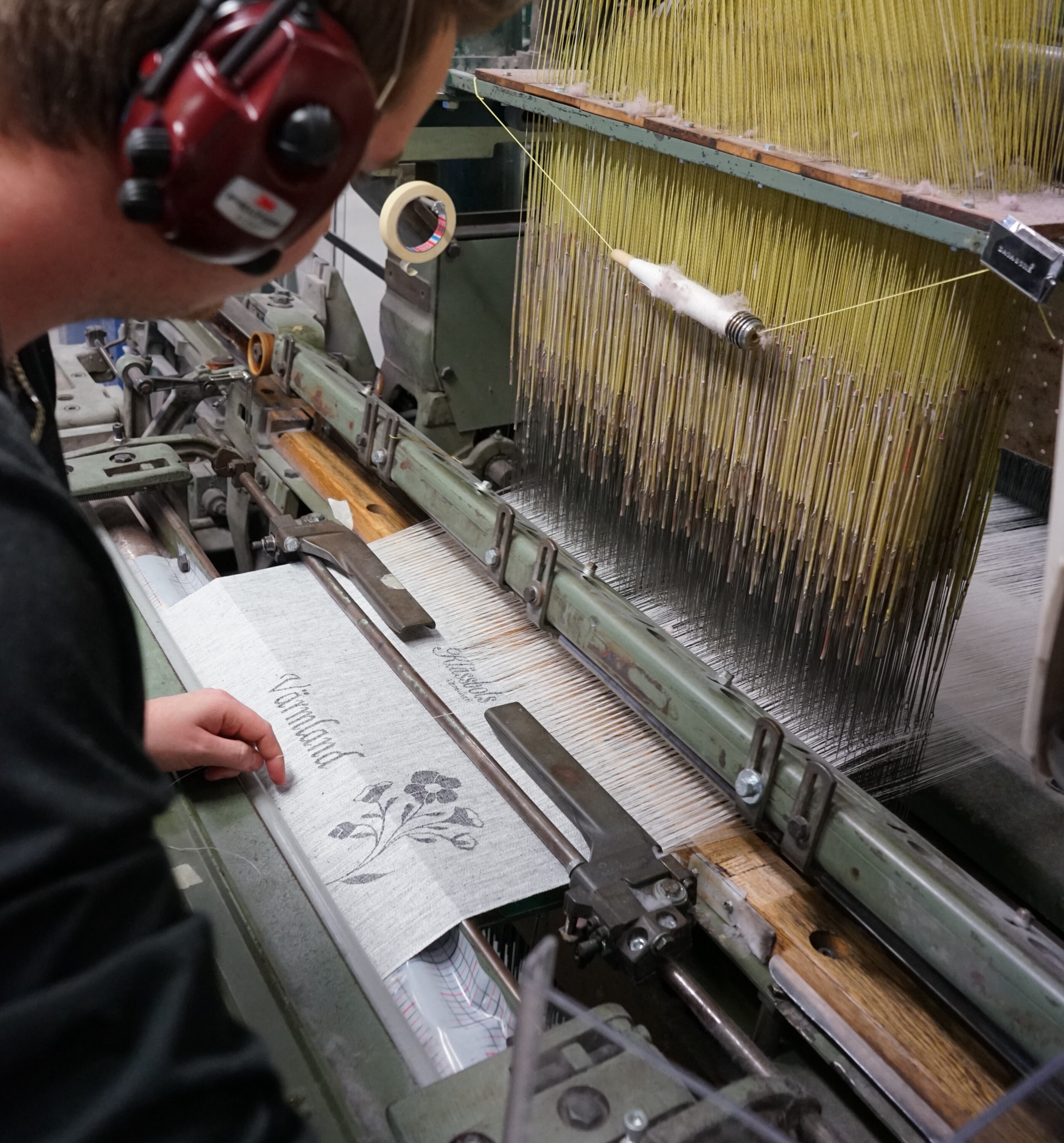 John at the loom. A textile is woven with a text that says Värmland 