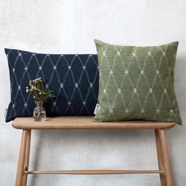 Decorative pillows standing on a stool, in the colors dark blue and green. Four-leaf clover pattern 