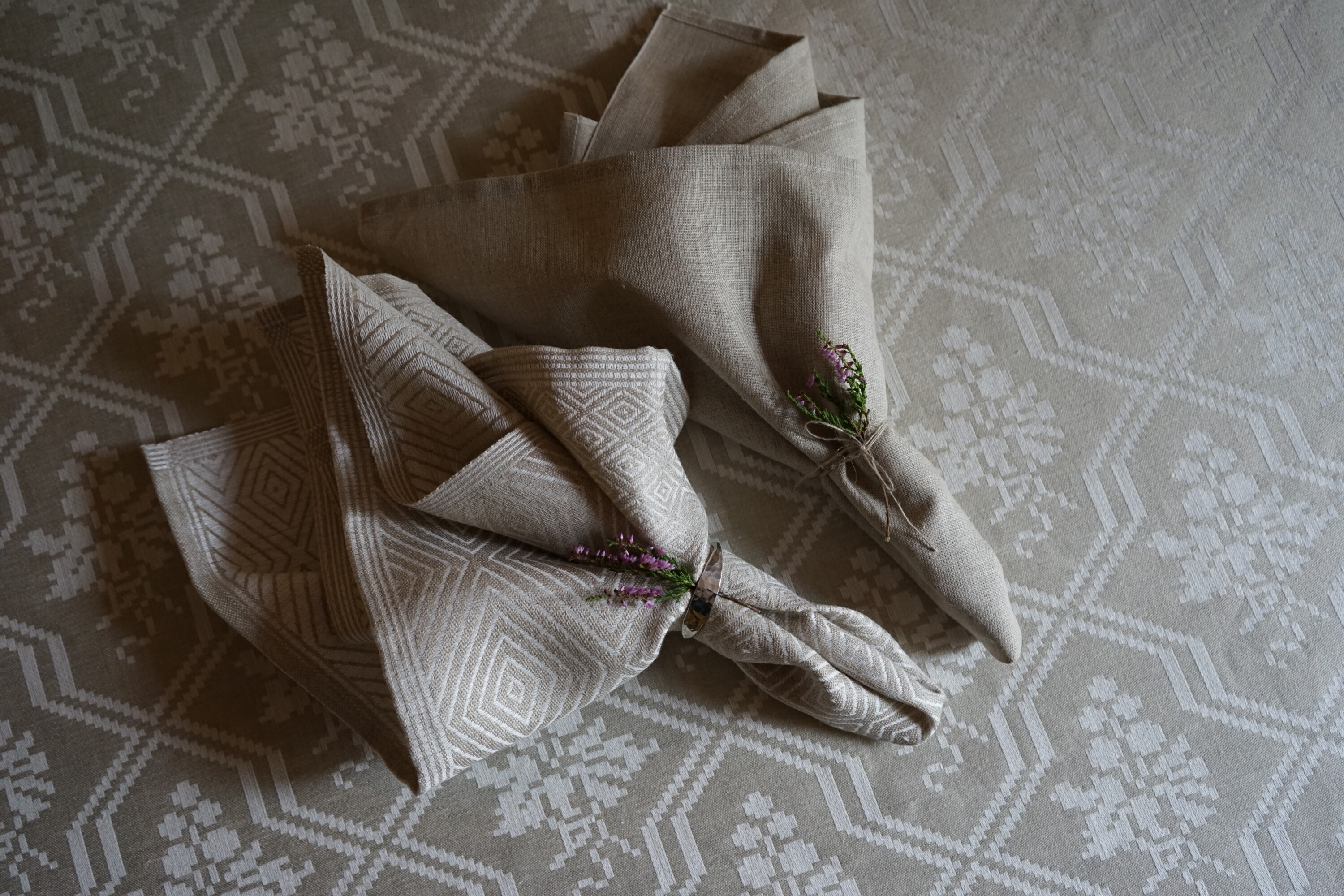 A Goose Eye and a Rustic napkin in a simple napkin fold, a lily adorns as a detail - klässbols linen weaving