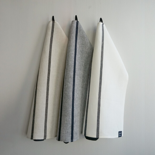 Sammlungsbild von Kristina Starks Glashandtüchern, die vor einem weißen Hintergrund hängen.