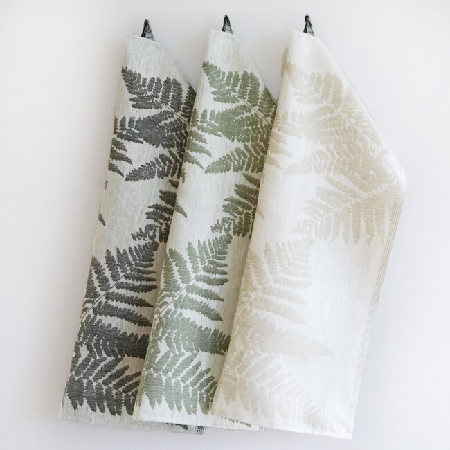 The linen towel fern in a fern pattern. Hanging against a light background. 